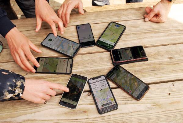 Des smartphones sont posés sur une table, ils affichent tous des cartes avec une géolocalisation en temps réel 